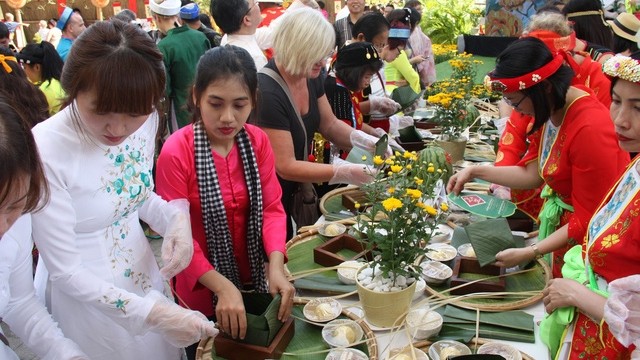 Des touristes étrangers font l’expérience du Têt vietnamien avec le festival du " Banh Chung ". Photo : TQ