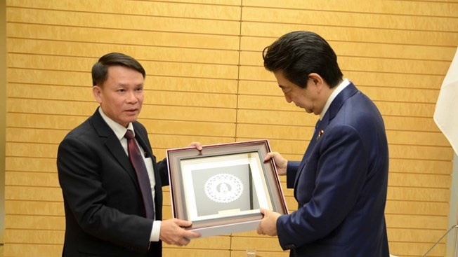 Nguyên Duc Loi, membre du Comité central du Parti communiste du Vietnam et directeur général de la VNA (à gauche), offre un souvernir au Premier ministre japonais, Shinzo Abe. Photo : VNA