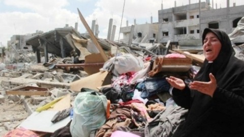 Une femme palestinienne à côté d’un bâtiment détruit par l’armée israélienne. Photo: NDEL.