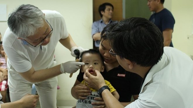 Des médecins vietnamiens et sud-coréens donnent une consultation médicale à un enfant atteint de bec-de-lièvre. Photo : huemed-univ.edu.vn