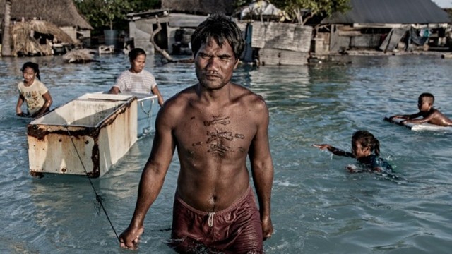 Une famille qui patauge dans l'eau de mer salée qui a inondé son village à Eita, Kiribati, le 30 septembre 2015. Photo : Getty Images
