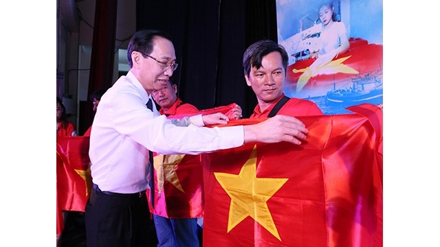 Le vice-président du Comité populaire municipal de Hô Chi Minh-Ville, Lê Thanh Liêm offre des drapeaux aux pêcheurs au large du district maritime de Cân Gio. Photo : NDEL.