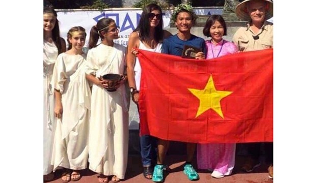 Trân Duy Quang (au t-shirt bleu) brandit le drapeau vietnamien après avoir terminé la course Spartathlon à Sparta, en Grèce, le 28 septembre 2019. Photo : vnexpress.net