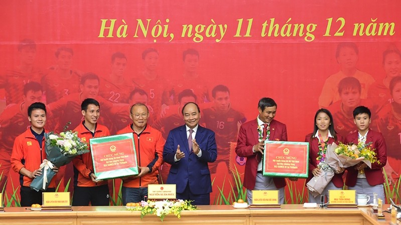 Le PM vietnamien Nguyên Xuân Phuc (au centre) félicite les sélections nationales de football masculine et féminine. Photo : NDEL.