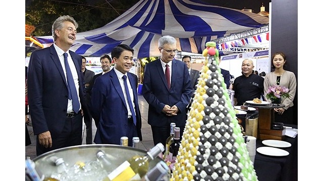 Le président du Comité populaire municipal de Hanoi, Nguyên Duc Chung et l’ambassadeur français au Vietnam Nicolas Warnery visitent un stand lors de la fête. Photo : ANTĐ.VN