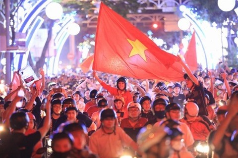 Des supporteurs vietnamiens dans la rue avec le drapeau national rouge à étoile jaune. Photo : VNA
