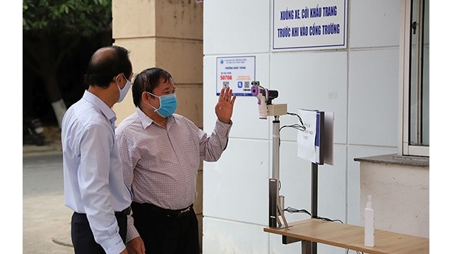 Le professeur Bùi Van Ga (à droite) vérifie le thermomètre à distance à l'Université des langues étrangères de Dà Nang. Photo : NDEL.
