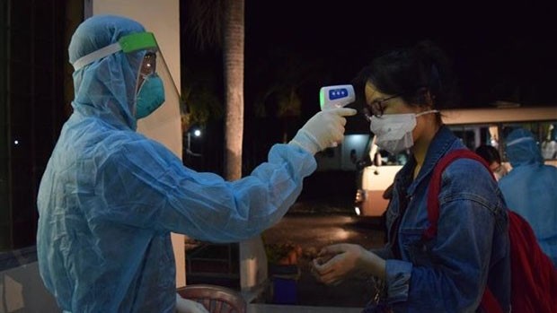 Un agent de santé vérifie la température corporelle d’une Vietnamienne de retour des Philippines. Photo : VNA.