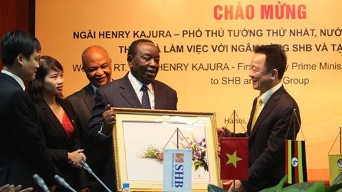 Dô Quang Hiên, président du Conseil d’administration de la SHB remet le cadeau de souvenir à Henry Kajura. Photo: dddn.com.vn.