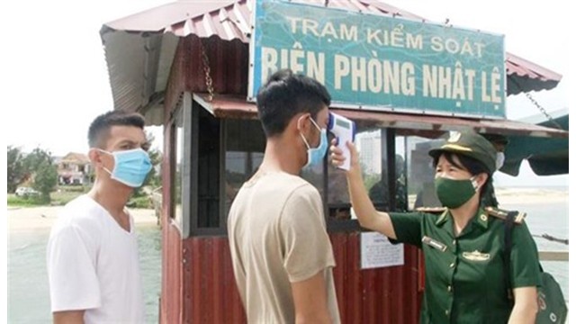 Prise de température corporelle d'un passager dans une station de contrôle épidémique du poste frontalier de Nhât Lê, province de Quang Binh (au Centre). Photo : VNA.