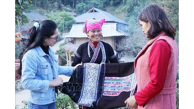 Une femme issue de l'ethnie Lu au village de Ban Hon dans le district de Tam Duong à Lai Châu, présente son produit de brocatelle aux visiteures. Photo : VNA.