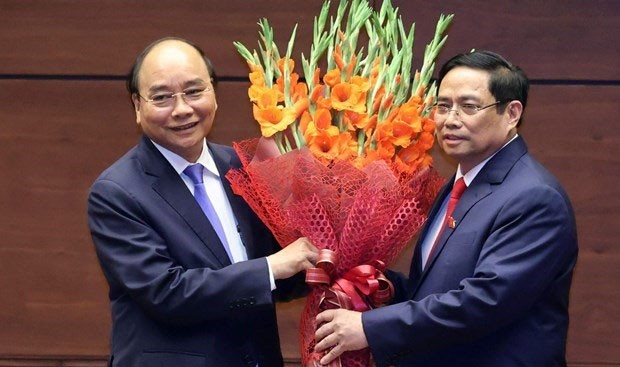 Le Premier ministre Pham Minh Chinh offre des fleurs au Président Nguyên Xuân Phuc. Photo : VNA.