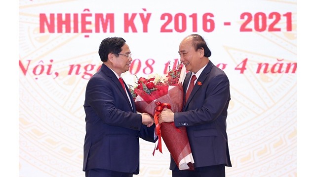 Le Premier ministre vietnamien Pham Minh Chinh (à gauche) offre des fleurs au Président du Vietnam Nguyên Xuân Phuc. Photo : VNA.
