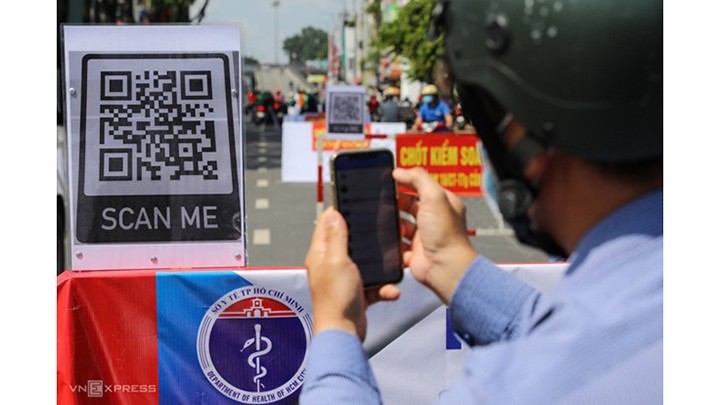Des gens scannent le code QR pour obtenir une déclaration médicale électronique lorsqu'ils passent le point de contrôle du Covid-19 à Hô Chi Minh-Ville, en juin 2021. Photo : VNA