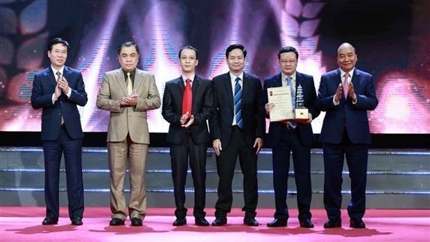 Le Président Nguyên Xuân Phuc (premier à droite) et Vo Van Thuong (premier à gauche), membre du Bureau politique, permanent du Secrétariat du Comité central (CC) du Parti, remettent le prix spécial au groupe d'auteurs du Journal Nhân Dân. Photo : VNA.