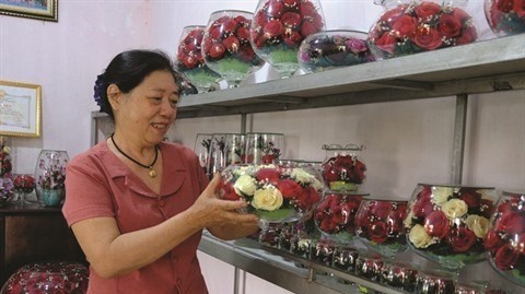 Lê Thi Viêt et ses fleurs placées sous verre. Photo : VNA.