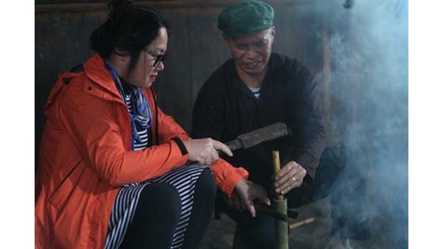Une visiteuse participe au processus de fabrication de tubes de thé sous l'enseignement d'un habitant local à Bac Hà. 
