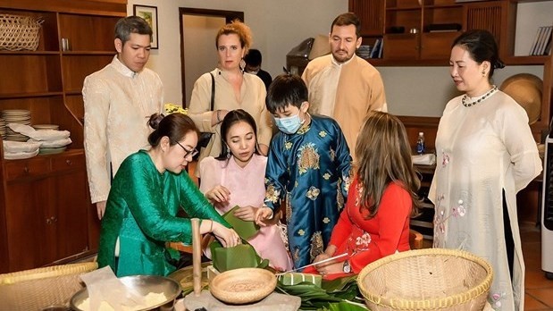Des amis étrangers sont invités à participer à des activités reconstituant le Têt traditionnel vietnamien, telles que l'emballage du “bánh chưng”. Photo : VNA.