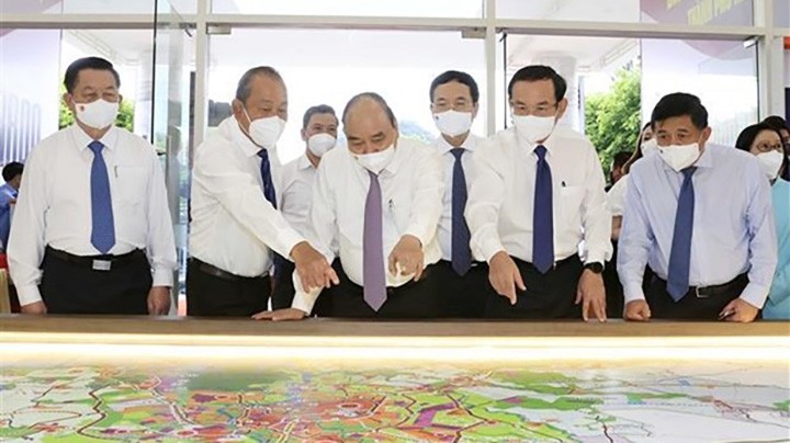 Le Président Nguyên Xuân Phuc scrute la carte de plannification pour les districts de Hoc Môn et Cu Chi, de Hô Chi Minh-Ville. Photo : VNA.
